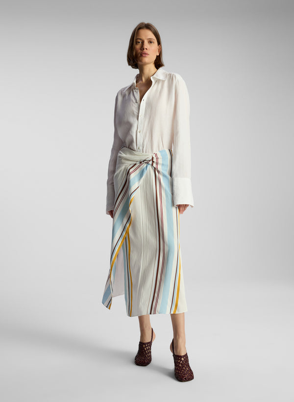 front view of woman wearing white button down shirt and multicolor striped skirt