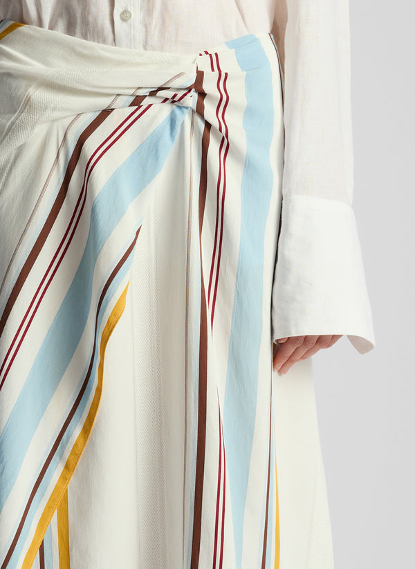 detail view of woman wearing white button down shirt and multicolor striped skirt