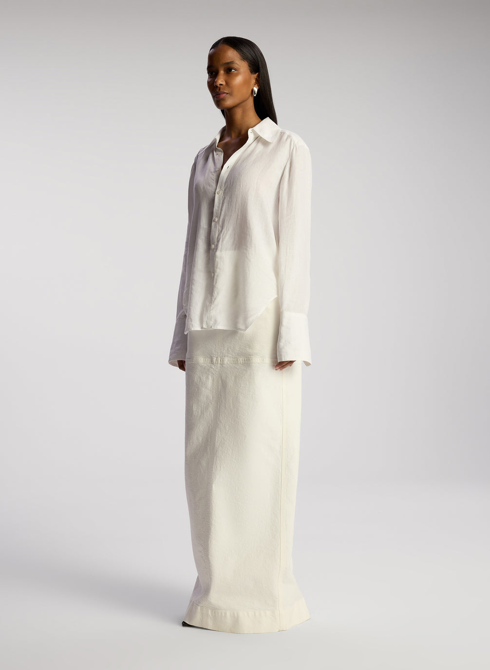 side view woman wearing white button down linen shirt and white maxi skirt