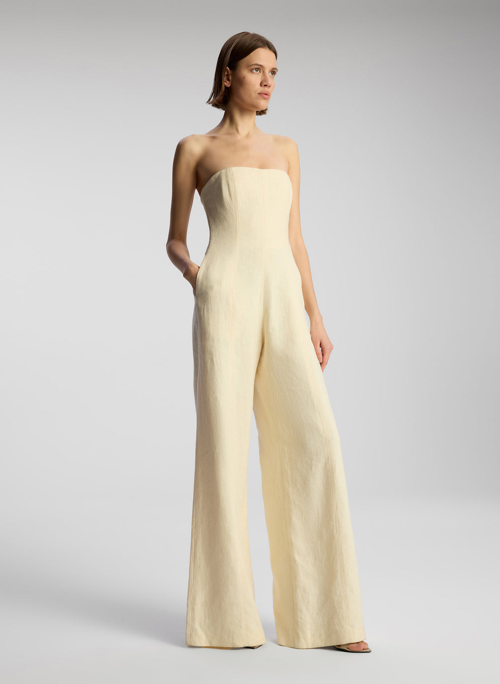 side view of woman wearing cream strapless jumpsuit