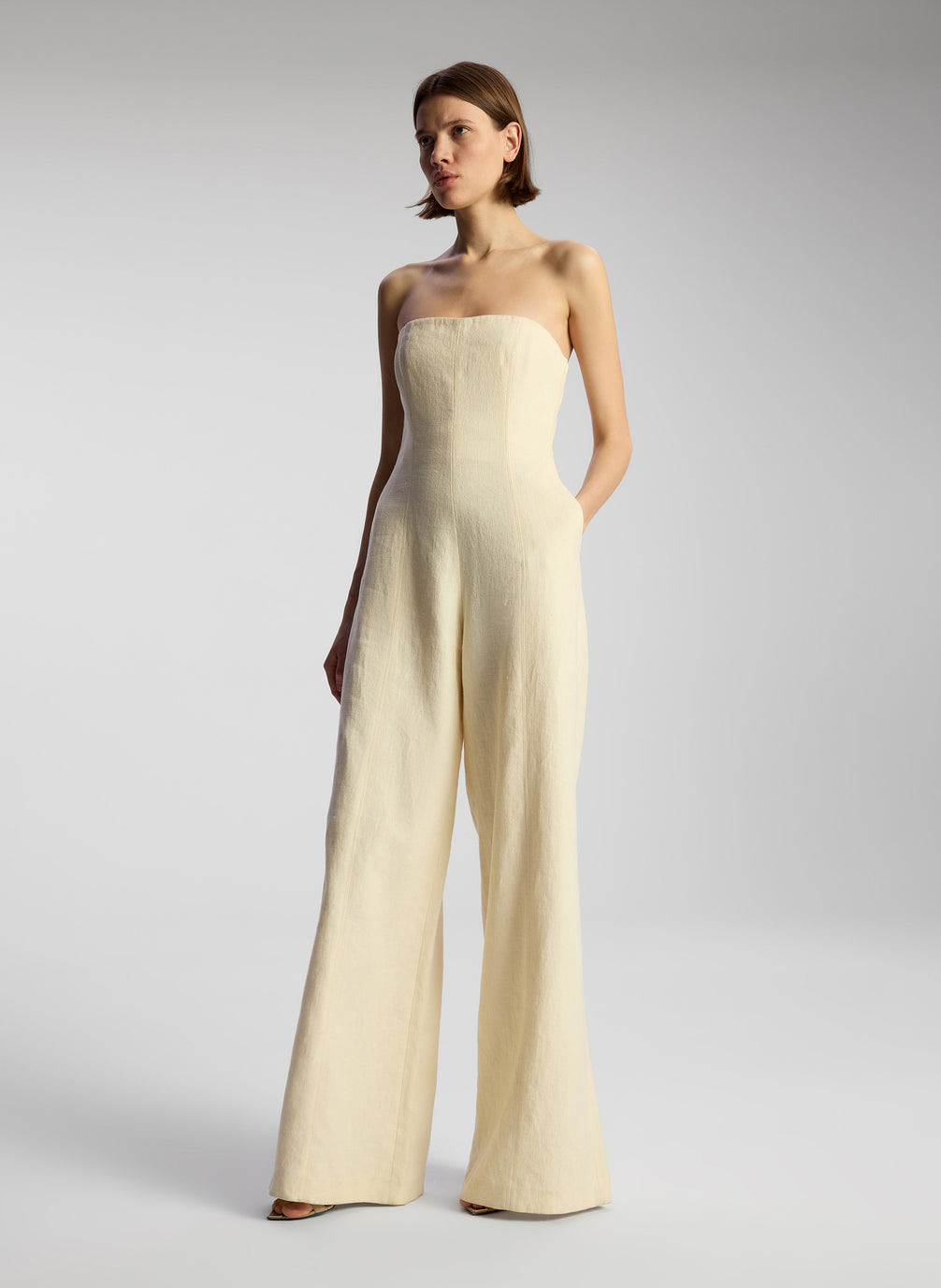 side view of woman wearing cream strapless jumpsuit