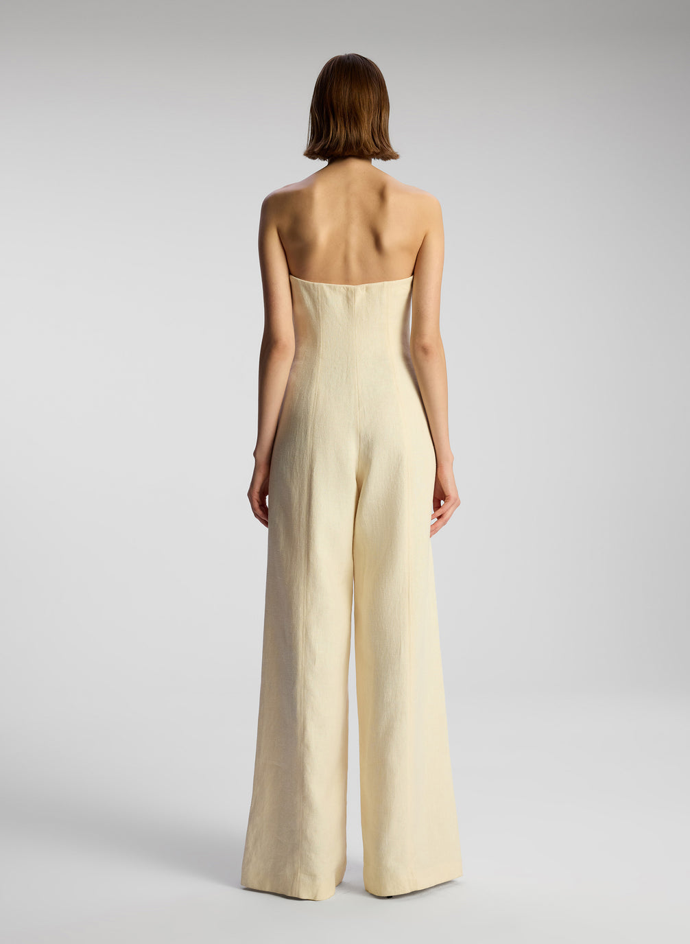 back view of woman wearing cream strapless jumpsuit