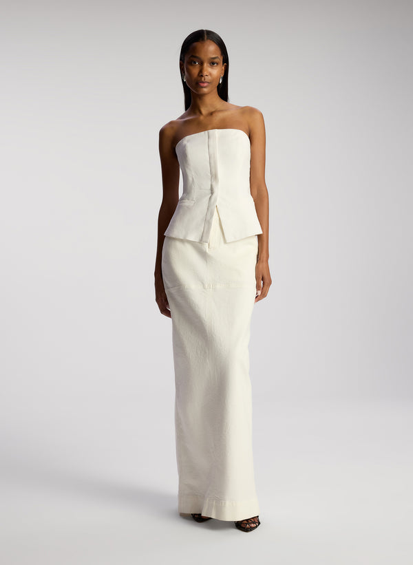 front view of woman wearing white strapless top and white maxi skirt