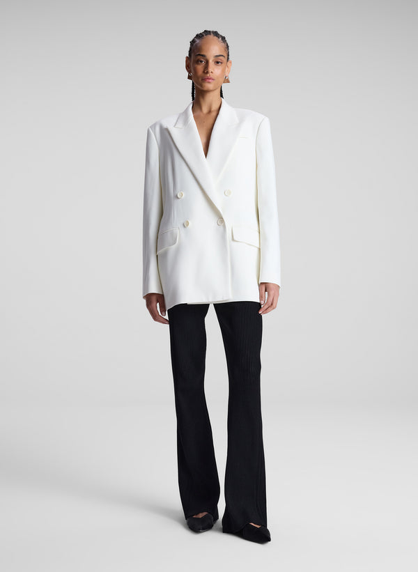 woman wearing white double breasted blazer and black flared pants