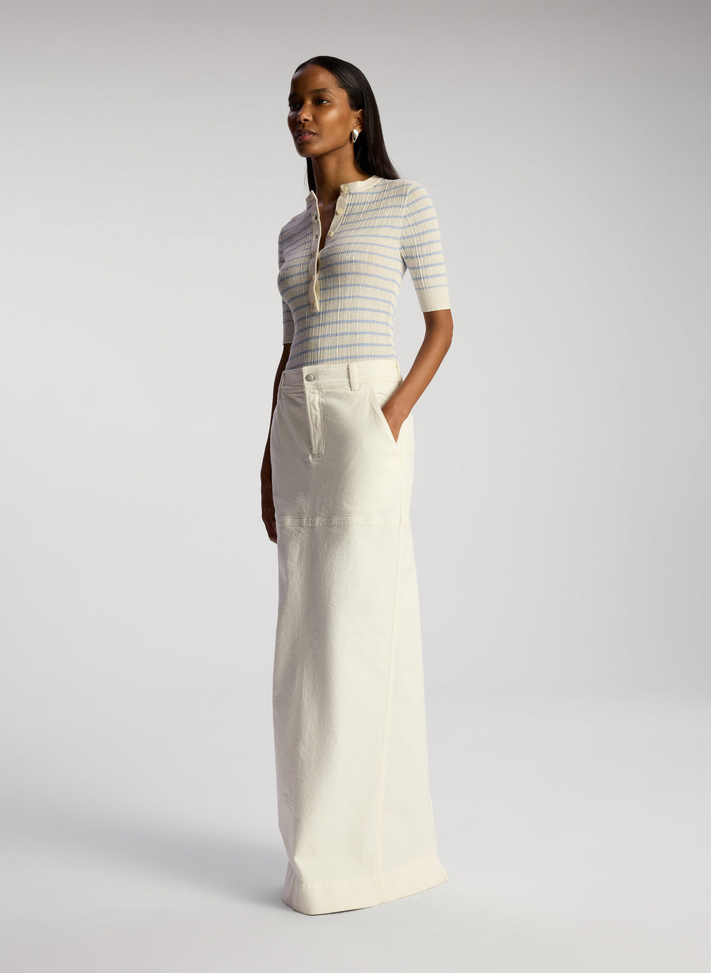 side view of woman wearing white and blue striped top and white maxi skirt