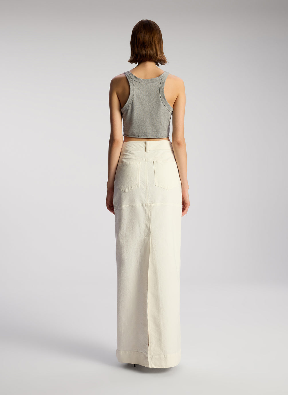 back view of woman wearing grey cropped tank and whit maxi skirt