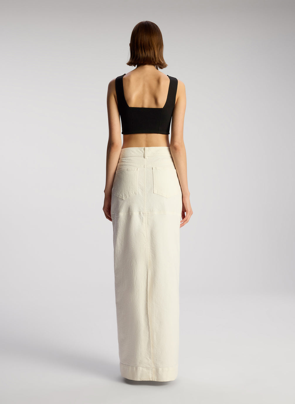 back view of woman wearing black cropped knit tank and white maxi skirt