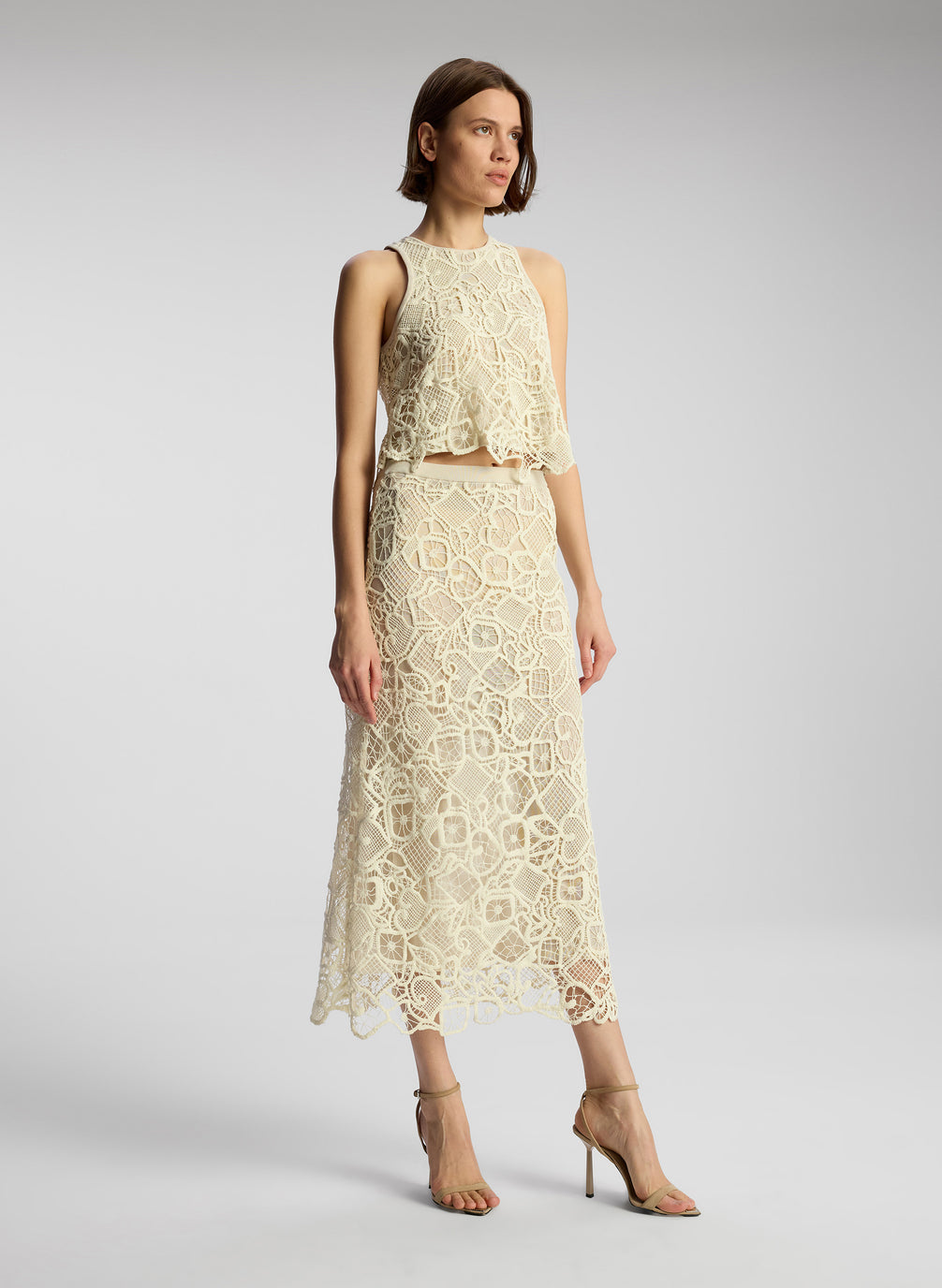 side view of woman wearing off white lace shirt and skirt set