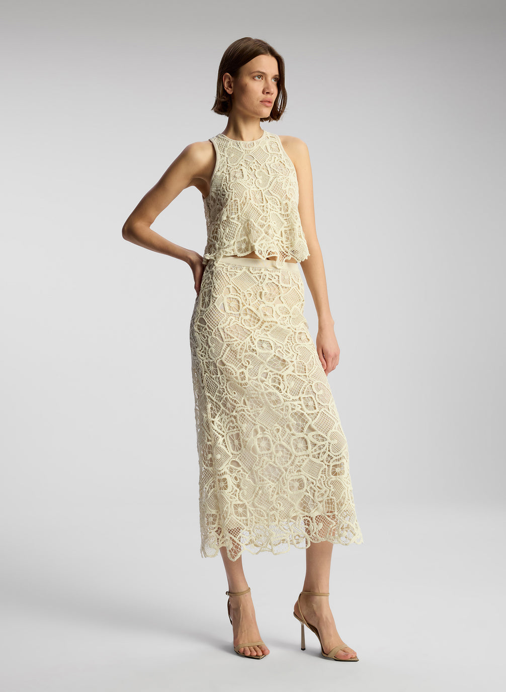 side view of woman wearing off white lace shirt and skirt set