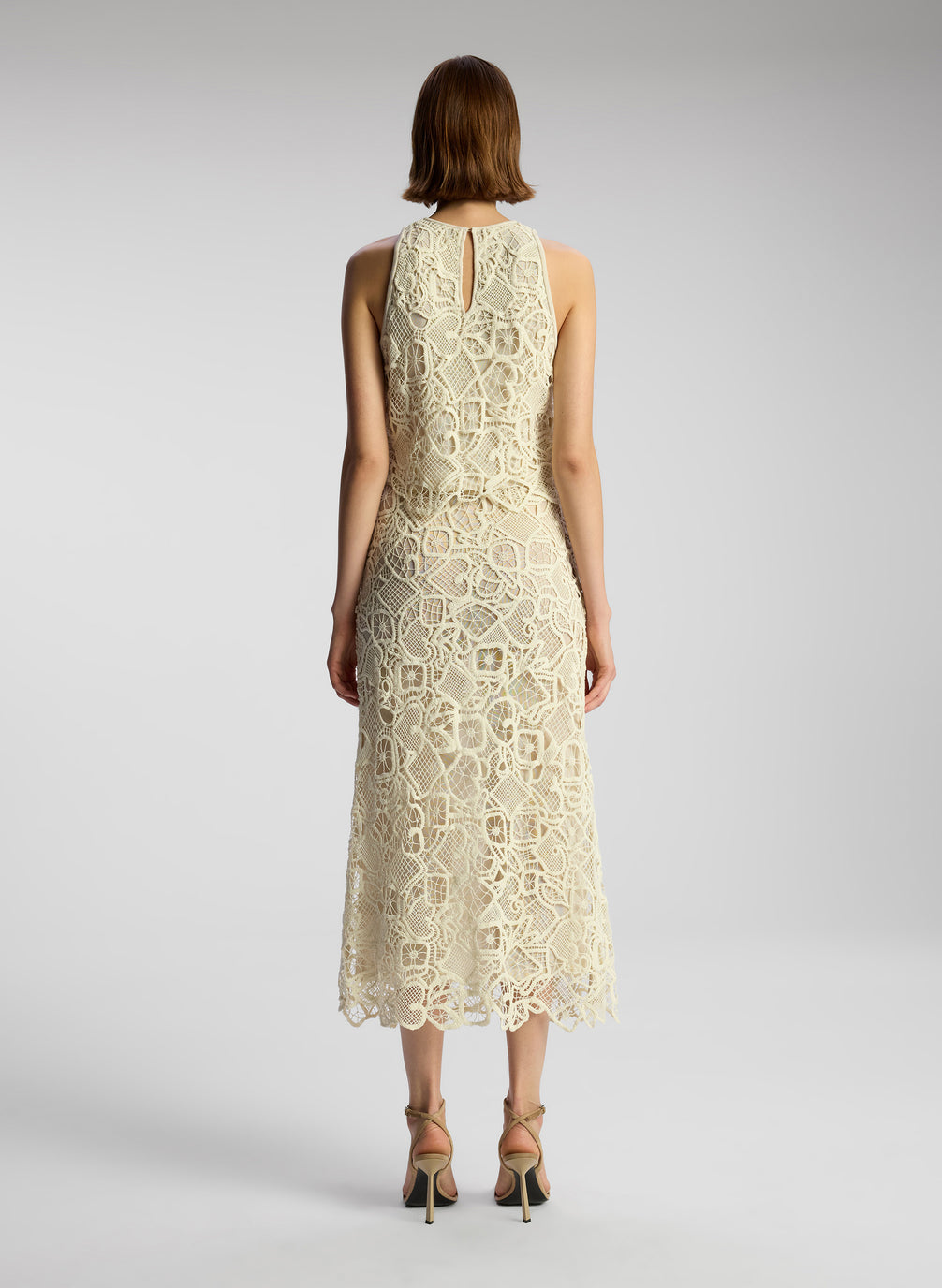 back view of woman wearing off white lace shirt and skirt set