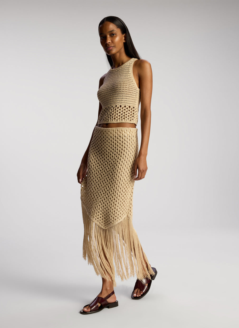 side  view of woman wearing tan crochet top and skirt set