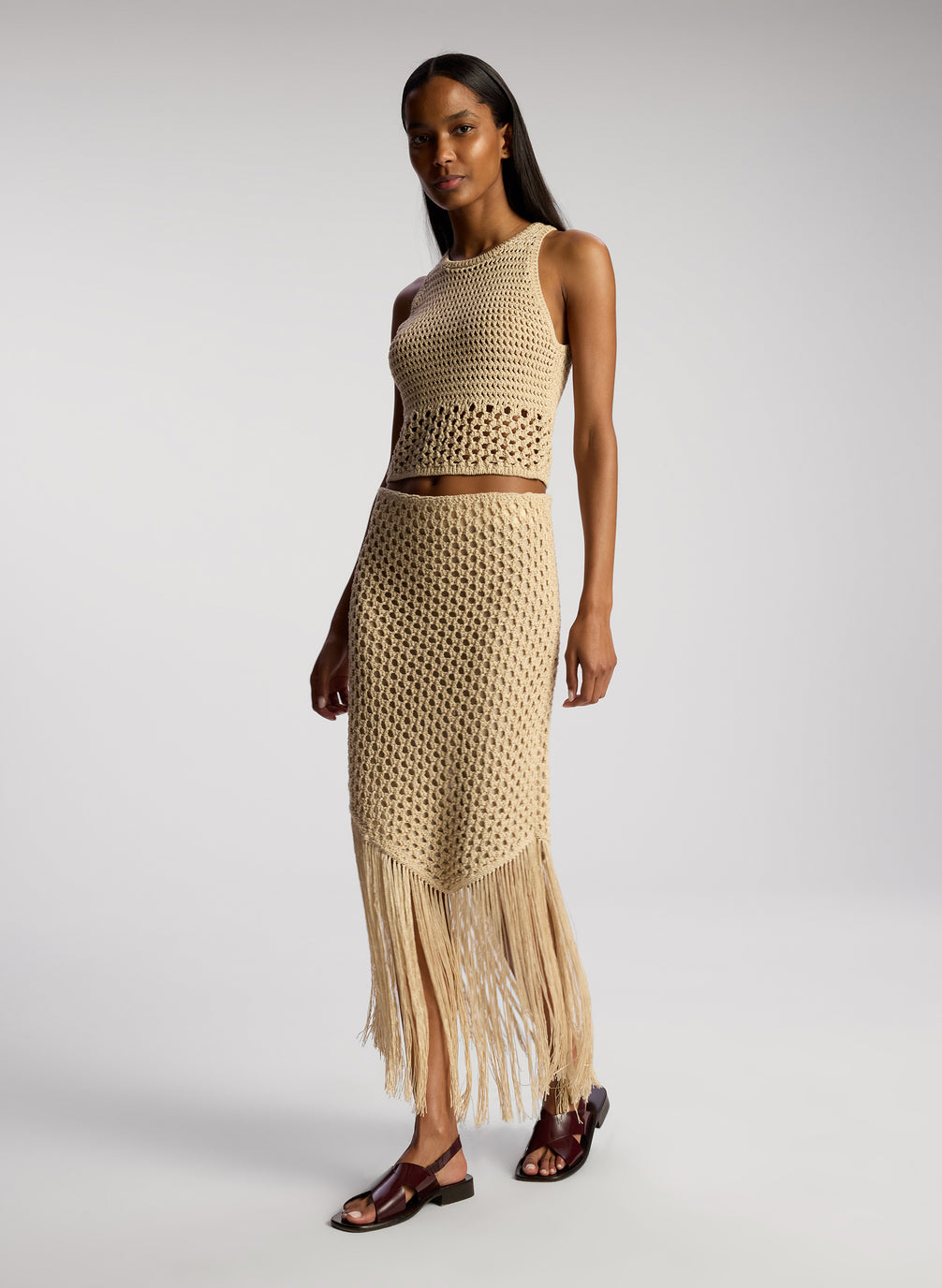 side view of woman wearing tan crochet top and skirt set