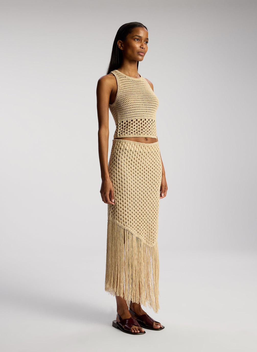 side view of woman wearing tan crochet top and skirt set
