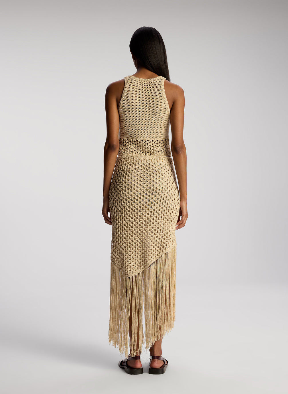 back view of woman wearing tan crochet top and skirt set