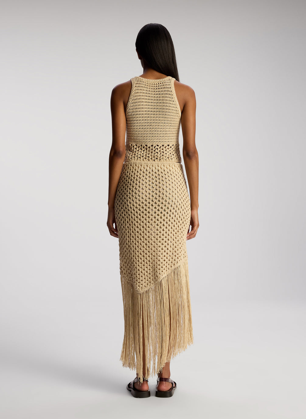 back view of woman wearing tan crochet top and skirt set