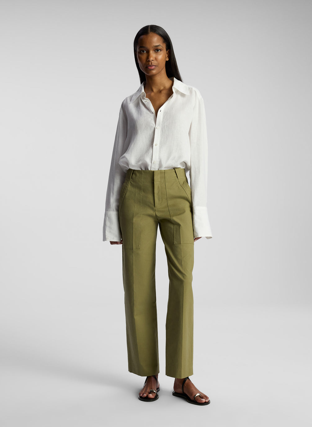front view of woman wearing white button down shirt and olive pants