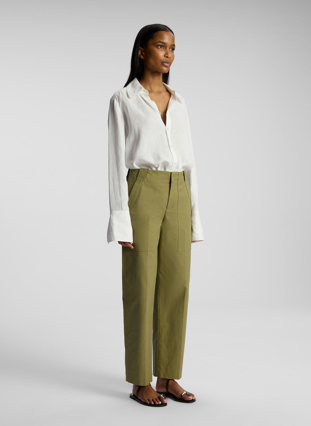 side view of woman wearing white button down shirt and olive pants