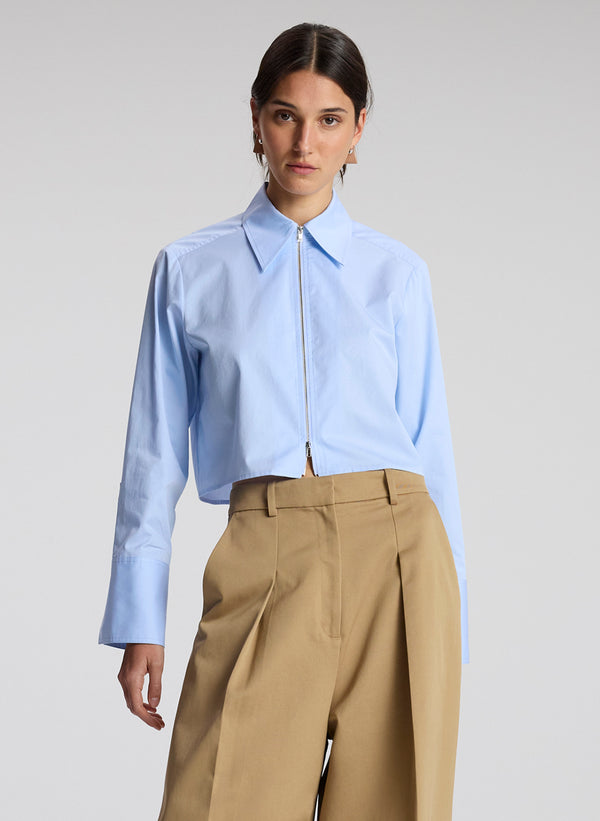 woman wearing light blue cropped zip collared shirt with khaki pants