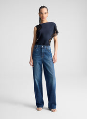 woman wearing navy blue satin and lace top with blue wide leg denim jeans