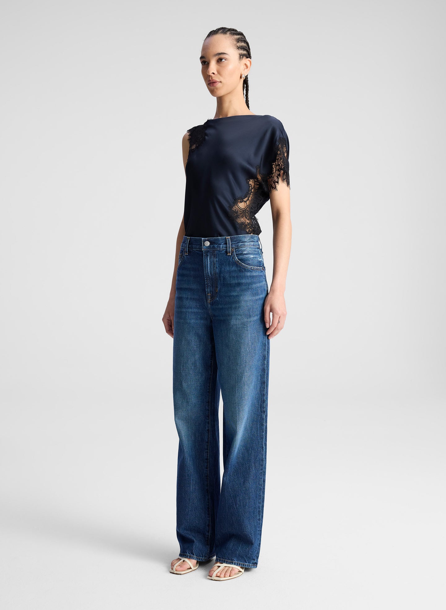 woman wearing navy blue satin and lace top with blue wide leg denim jeans