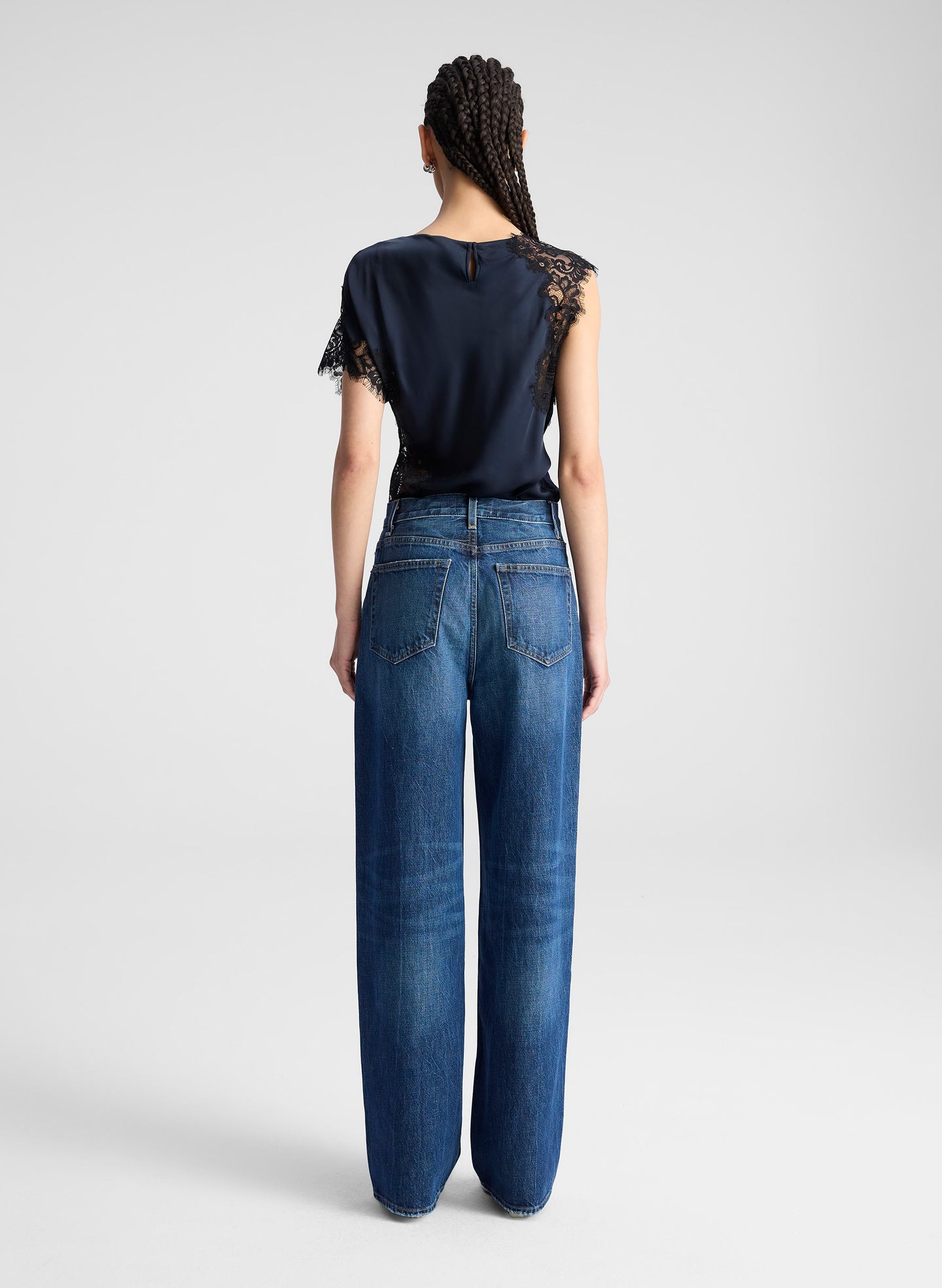 woman wearing navy blue satin and lace top with blue wide leg denim jeans