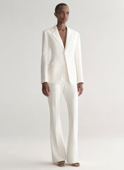 Person wearing a white suit on a plain background