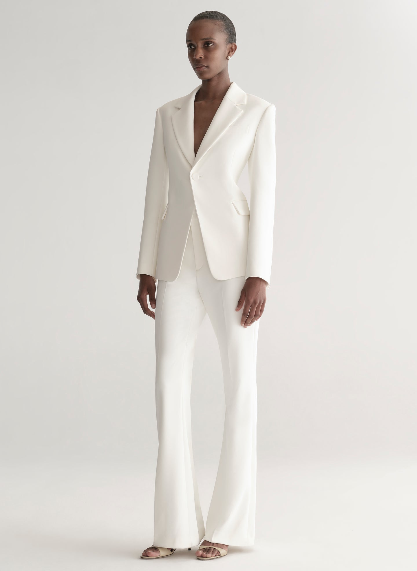 Woman wearing a white suit on a plain background