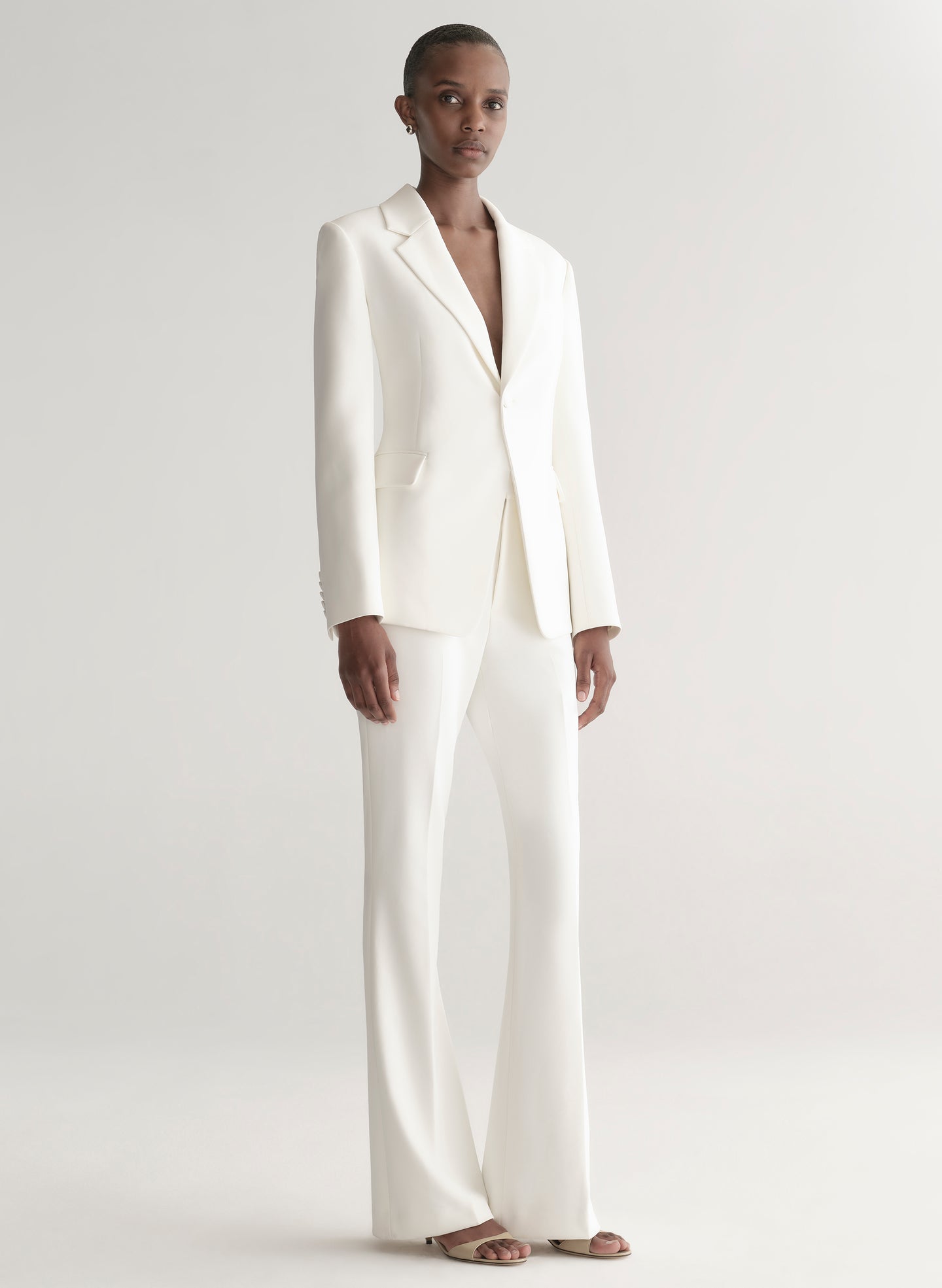 Person wearing a white suit on a plain background