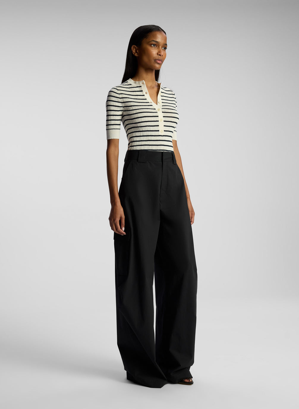 side view of woman wearing striped top and black cargo pants
