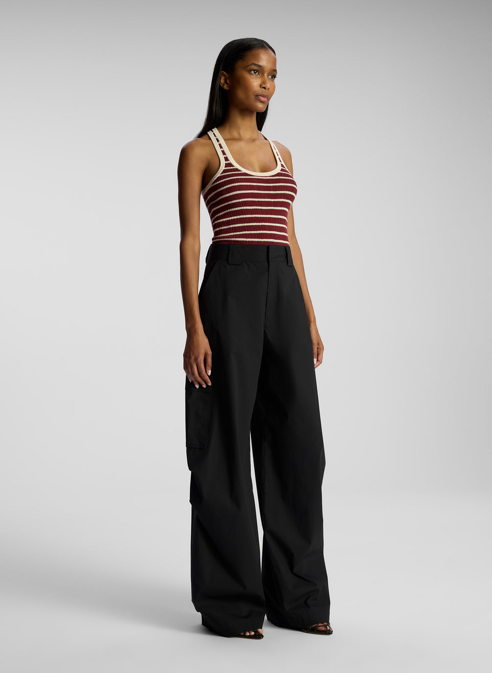 side view of woman wearing burgundy striped tank top and black cargo pants