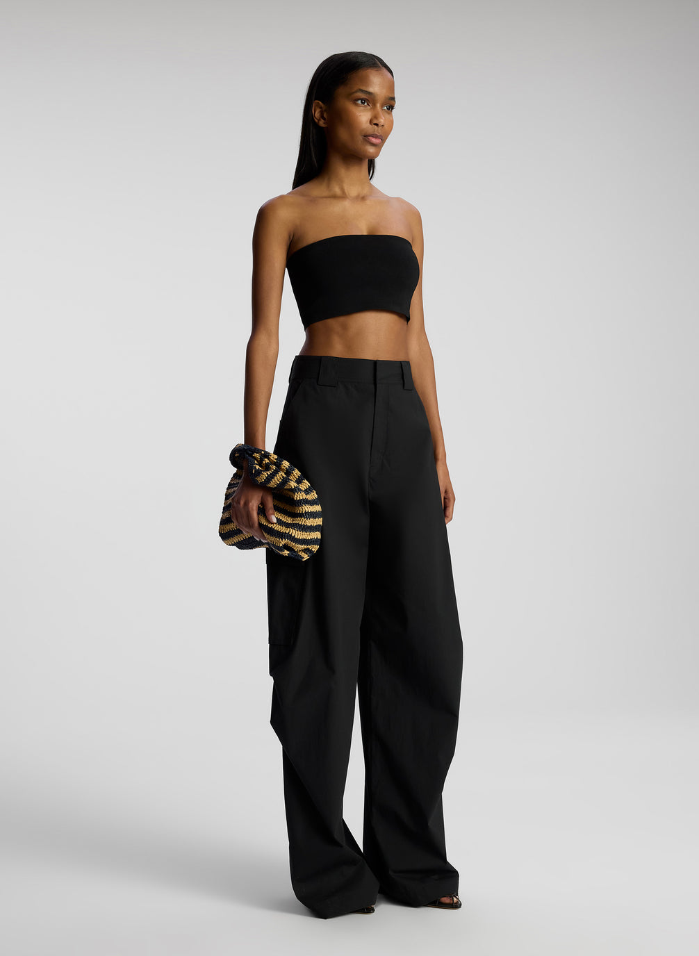side view of woman wearing black strapless crop top and black pants