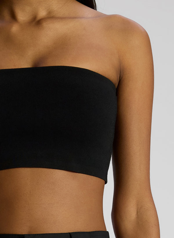 detail view of woman wearing black strapless crop top and black pants