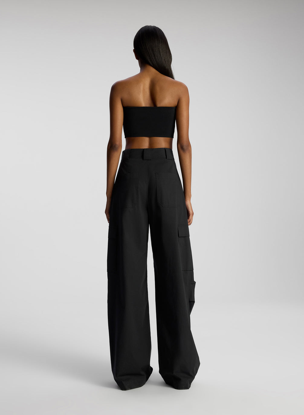 back view of woman wearing black strapless crop top and black pants