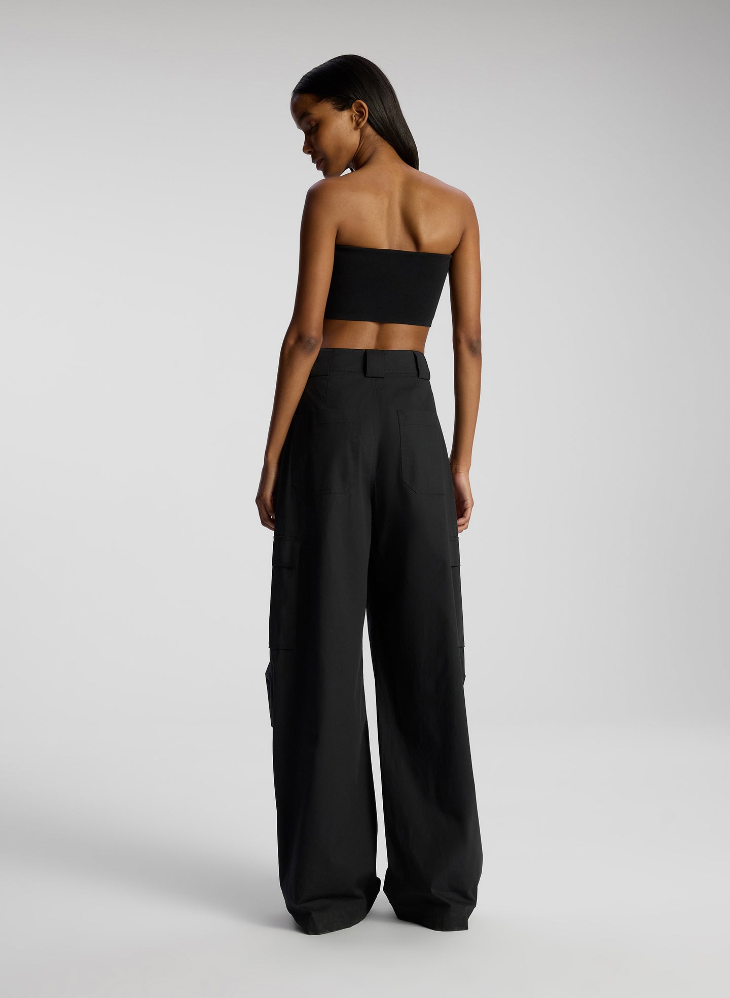 back view of woman wearing black strapless crop top and black pants