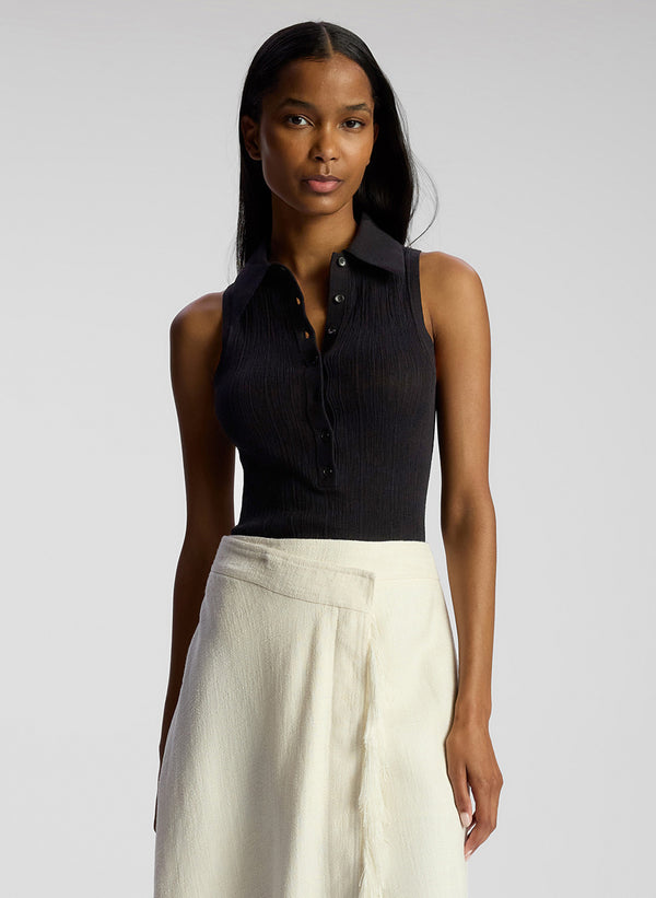 front view of woman wearing black collared sleeveless shirt and white skirt