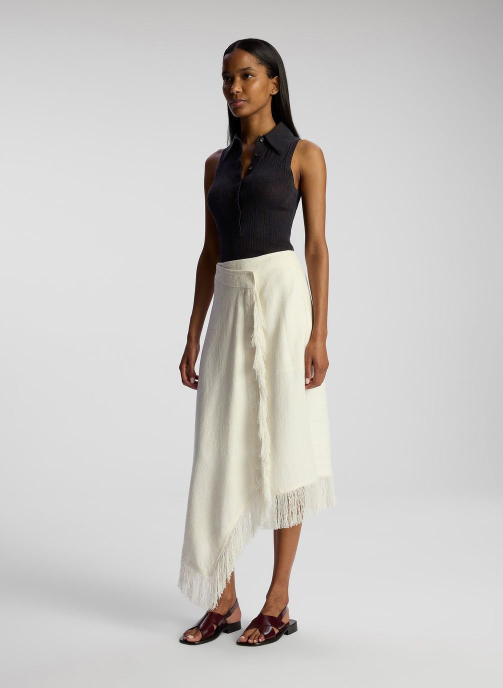 side view of woman wearing black collared sleeveless shirt and white skirt