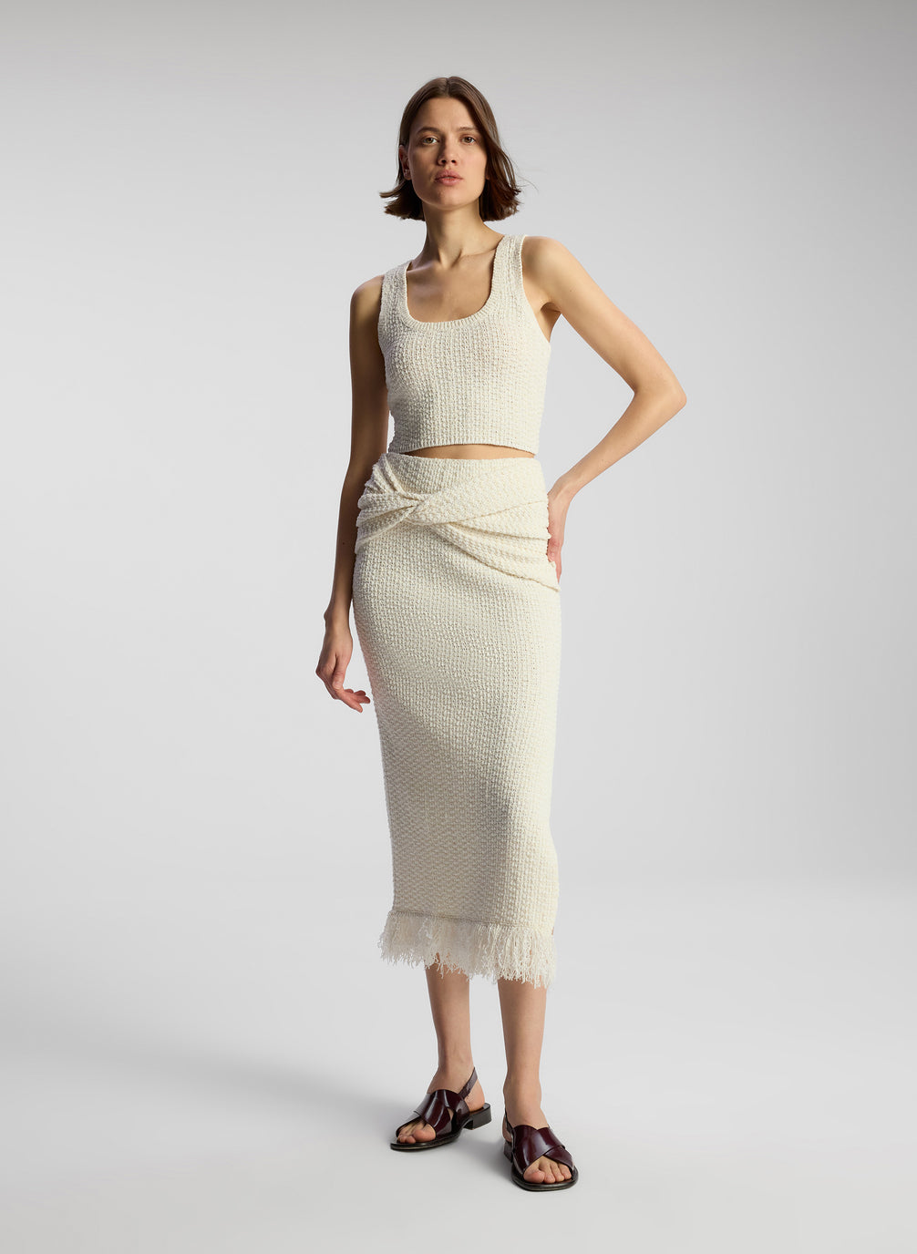 front view of woman wearing white knit sleeveless top and matching skirt