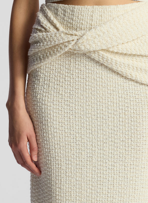 detail view of woman wearing white knit sleeveless top and matching skirt