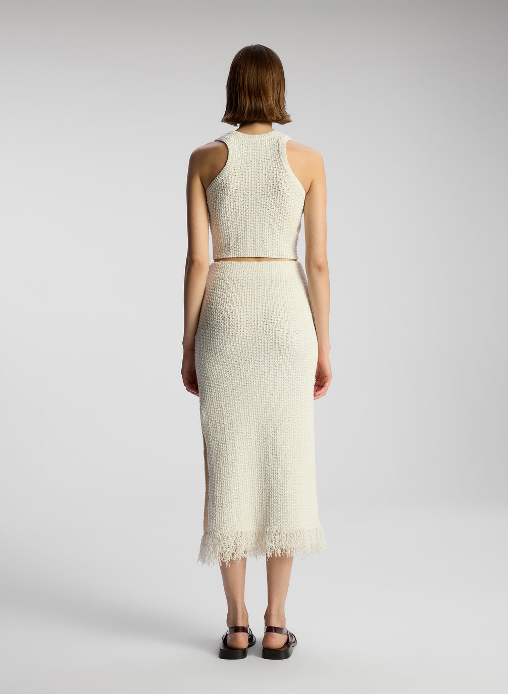 back view of woman wearing white knit sleeveless top and matching skirt