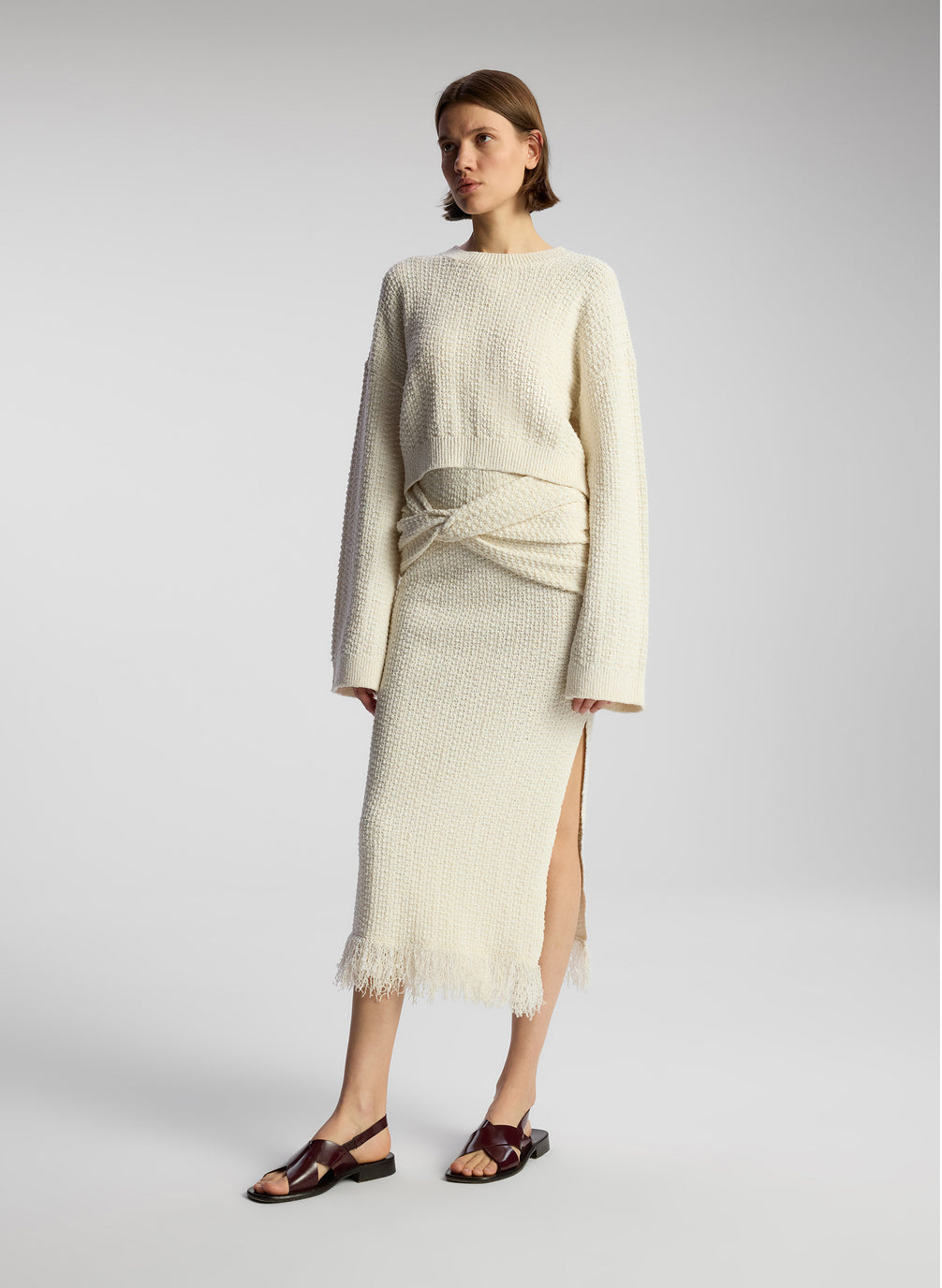 side view of woman wearing white pullover sweater and matching midi skirt