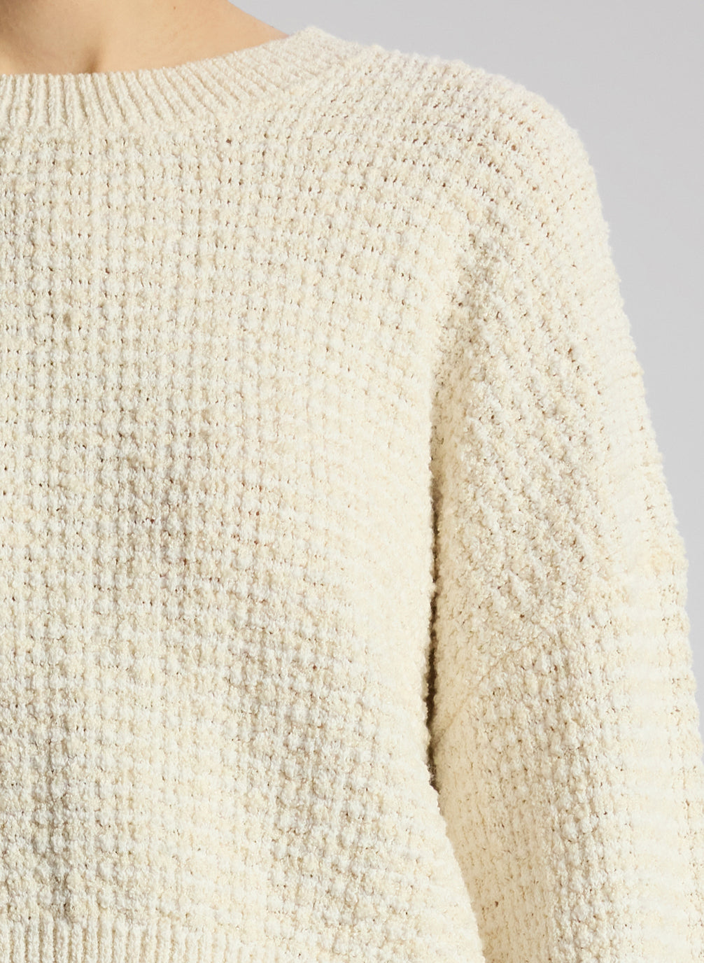 detail view of woman wearing white pullover sweater and matching midi skirt