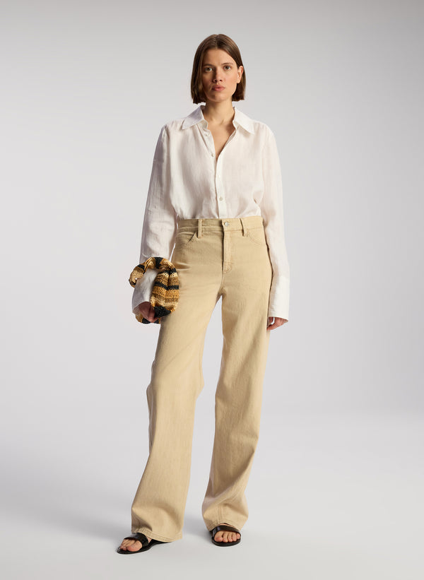 front view of woman wearing white button down shirt and tan pants