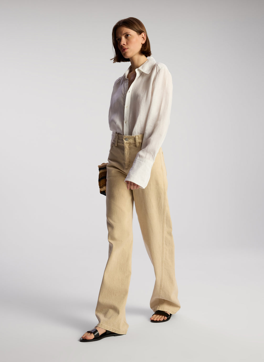 side view of woman wearing white button down shirt and tan pants