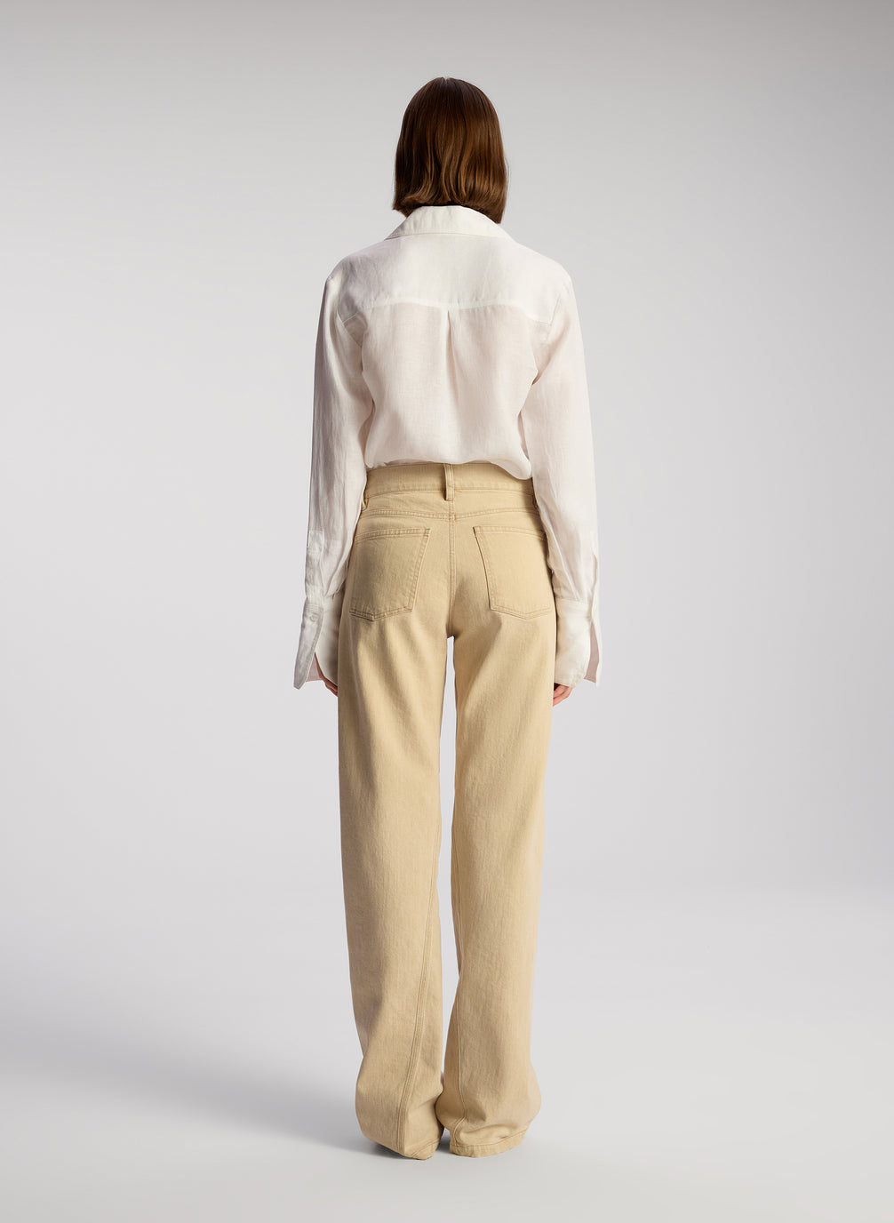 back view of woman wearing white button down shirt and tan pants