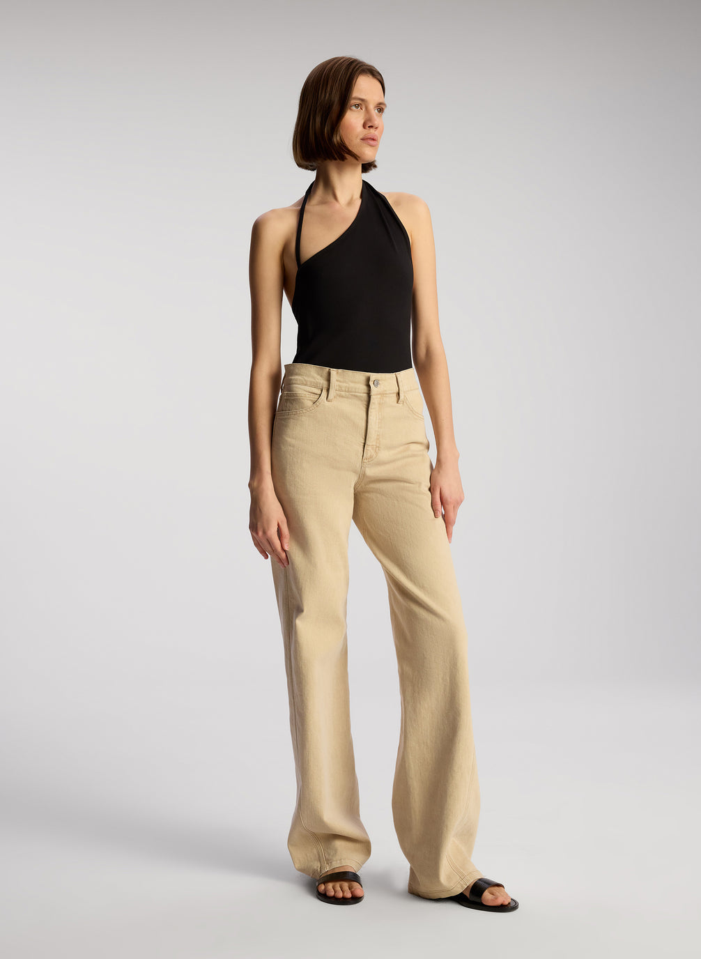 side view of woman wearing black asymmetric tank and tan pants