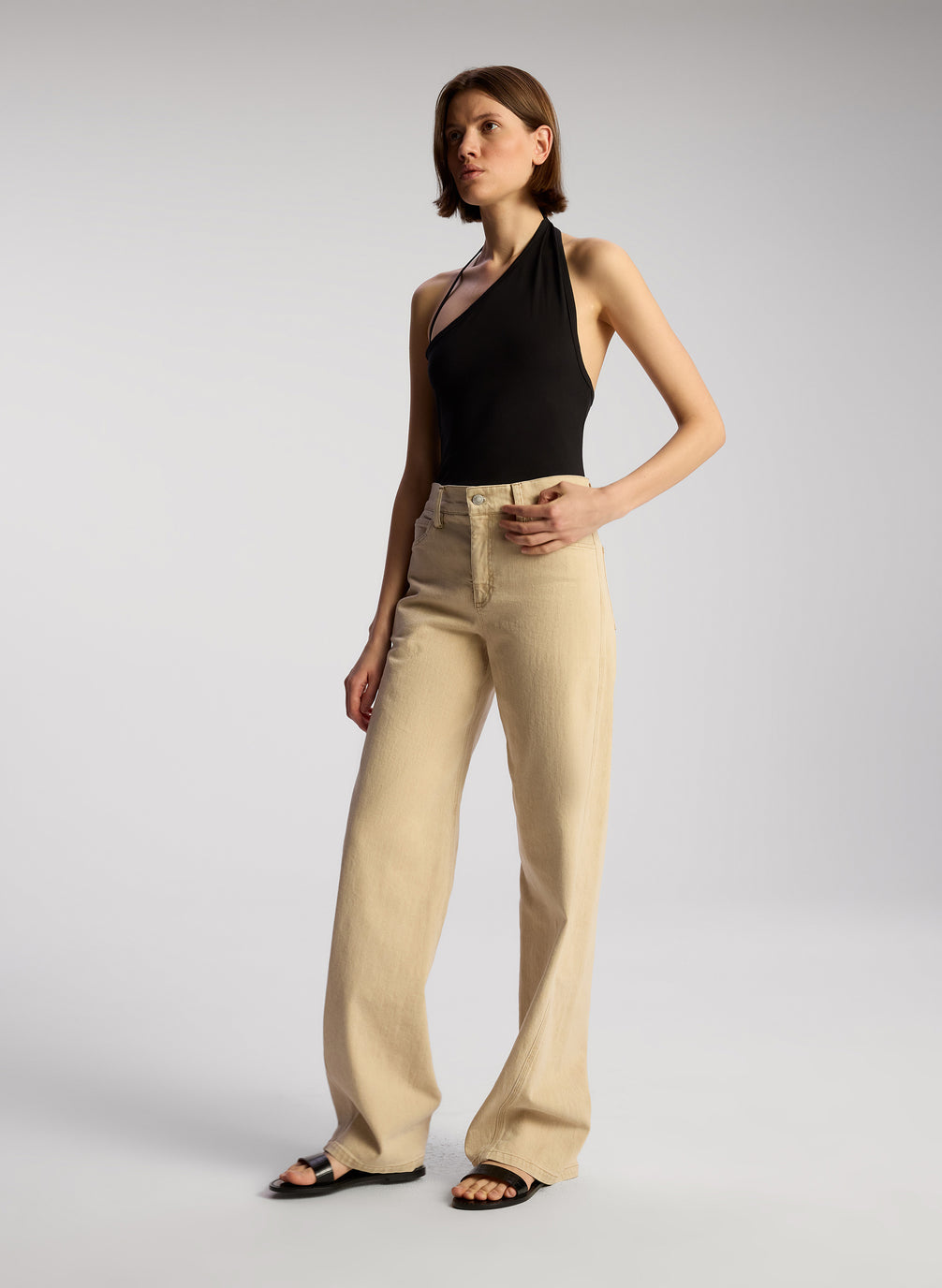 side view of woman wearing black asymmetric tank and tan pants