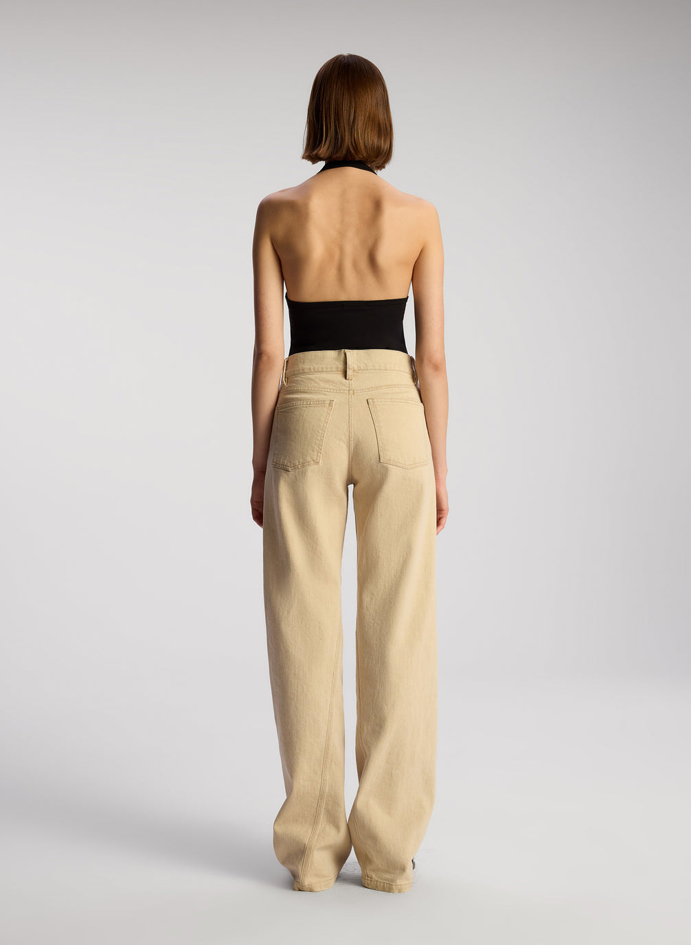 back view of woman wearing black asymmetric tank and tan pants