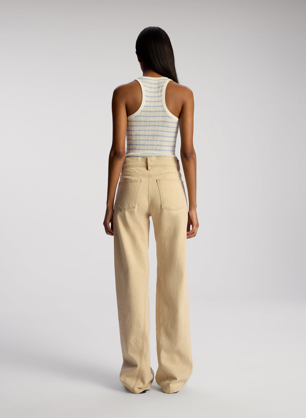 back view of woman wearing light blue and white striped tank top and tan pants
