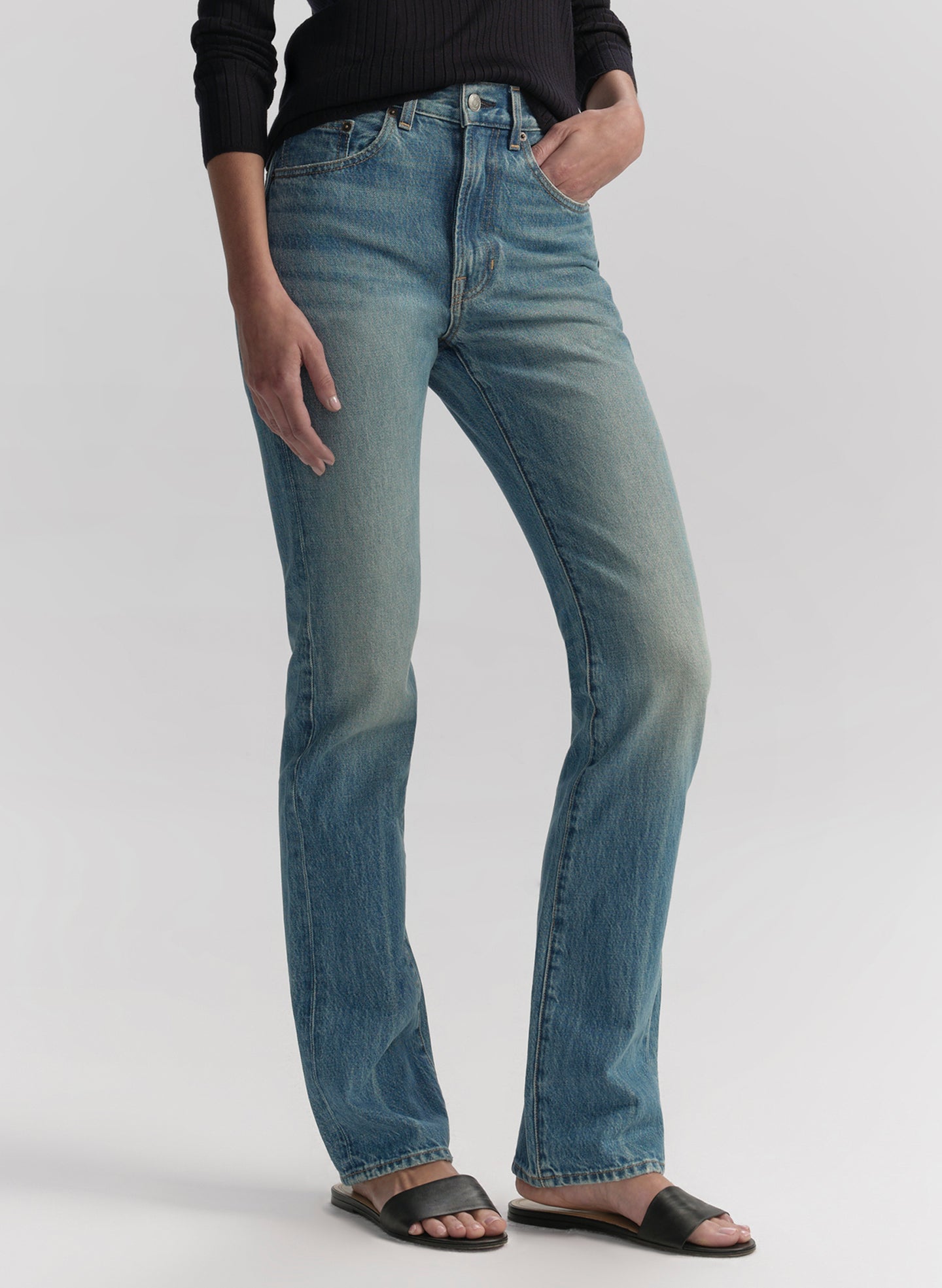 Woman wearing a navy blue shirt and blue jeans on a white background