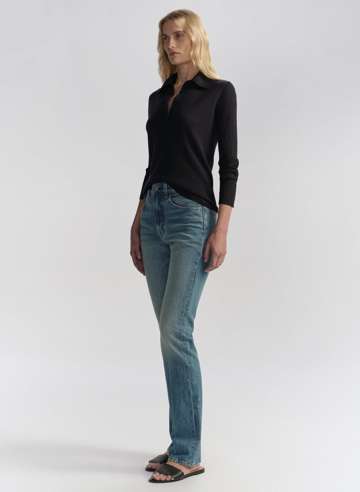 Woman wearing a navy blue shirt and blue jeans on a white background